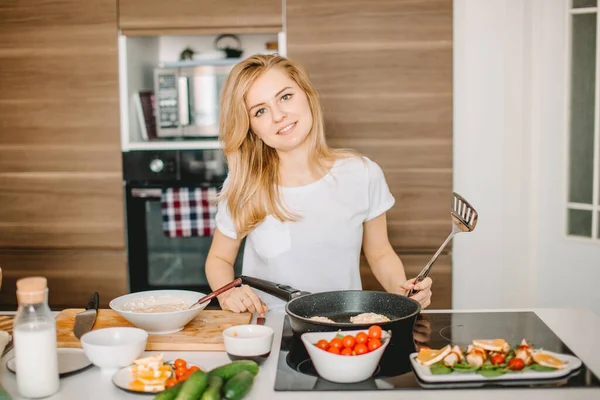 Belle fille blonde debout près de la poêle dans la cuisine moderne — Photo