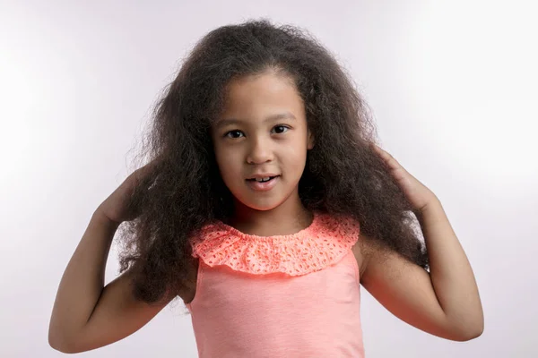 Aangenaam mooi meisje aanraken van haar haar en kijken naar de camera — Stockfoto