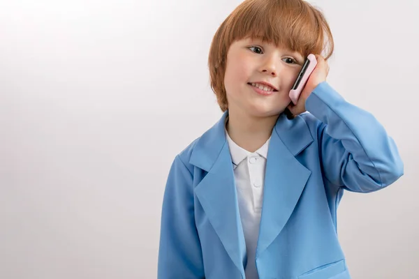 Egy jóképű, vörös hajú gyerek telefonál egy kicsit. — Stock Fotó