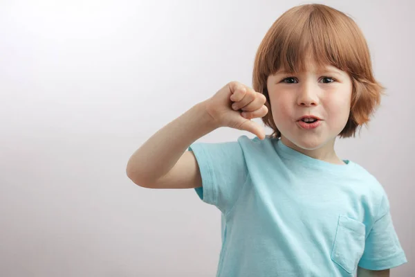 El niño está mostrando el pulgar hacia abajo. niño no le gusta algo. — Foto de Stock