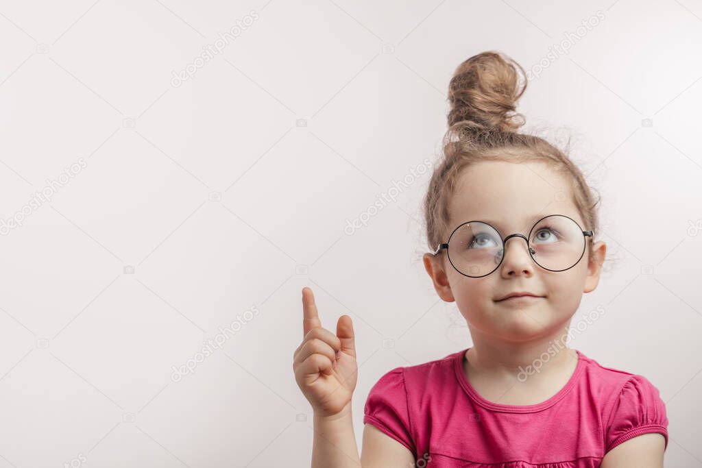 beautiful ginger kid in glasses with rised finger looking up