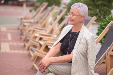 Şık giyinmiş hoş, olgun bir kadın konseri dışarıda bekliyor.