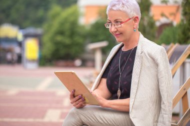 Parkta tabletle çalışan mutlu bir yüzü olan hoş bir iş kadını.