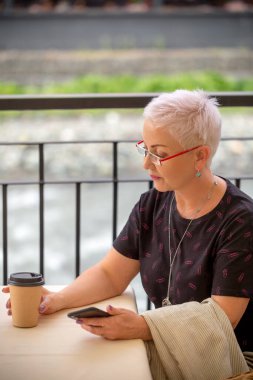 Sarı saçlı kadın kapuçino bardağına bakıyor.