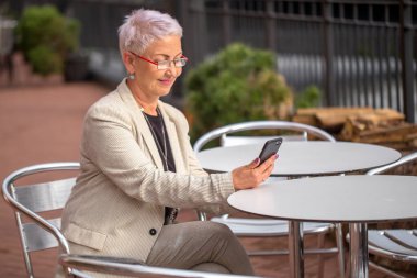 Moda yaşlısı kadın Skype 'tan konuşuyor. Kahve dükkanından bir arkadaşı.