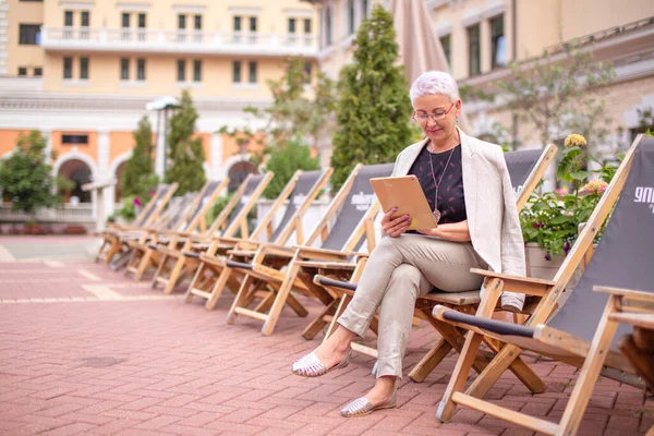 En vacker ljushårig kvinna tittar på bilderna från surfplattan — Stockfoto