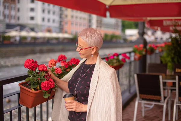 Mogen kvinna ser efter blommorna på caféet — Stockfoto