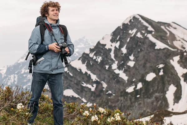 Fröhlicher Backpacker hält seine Digitalkamera während er auf dem Hügel steht — Stockfoto