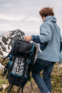 Genç turist ağır sırt çantasını tutuyor ve harika bir yerden ayrılıyor.