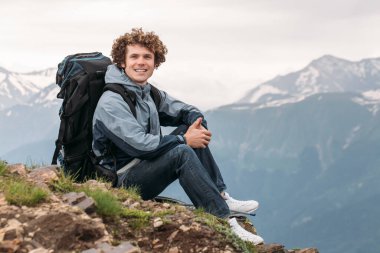 Sırt çantalı deneyimli bir gezgin dışarı çıkıp kameraya bakıyor.