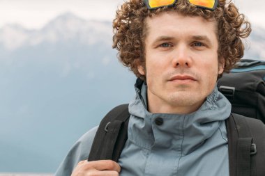 Kıvırcık saçlı, şık ceketli, yakışıklı, harika bir gezgin.