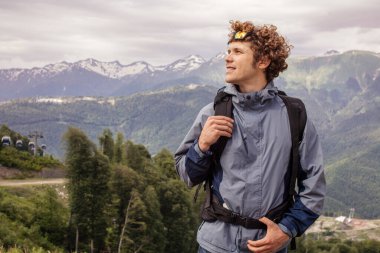 Sırt çantalı yakışıklı genç adam dağlarda yürüyor.