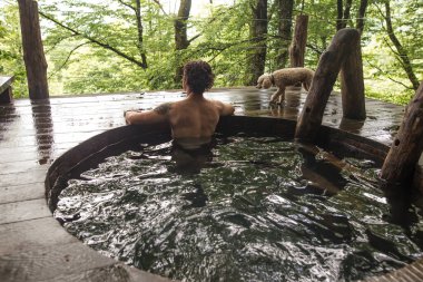 Düşünceli çıplak adam ormandaki kuşları izliyor.