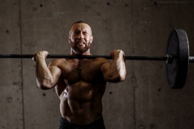 Spor kulübünde halterli gergin yüzüyle muhteşem bir vücut geliştirici.