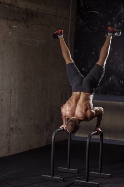 Formda adam spor salonunda paralel barlar kullanıyor.