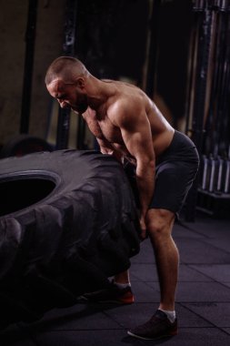 Ağır lastikli kasıtlı bir sporcu. Sporcu arkadaşlar için atölyeyi gösteriyor