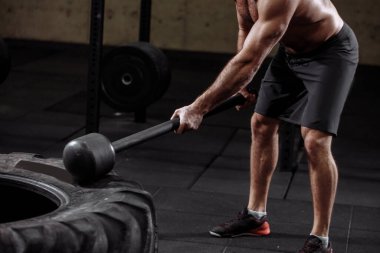 Kesilmiş yan görüntü. Lastik ve balyozlu vücut geliştirici.