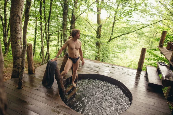 Sexy schöner Kerl schaut nach oben und steht auf der Treppe des Whirlpools — Stockfoto