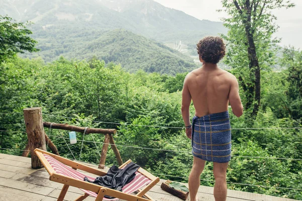 Junger Mann mit lockigem Haar schreckt vor der atemberaubenden Landschaft zurück — Stockfoto