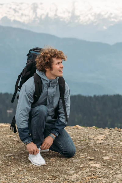 Ein gutaussehender Tourist bindet sich auf Reisen die Schnürsenkel an den Schuh — Stockfoto