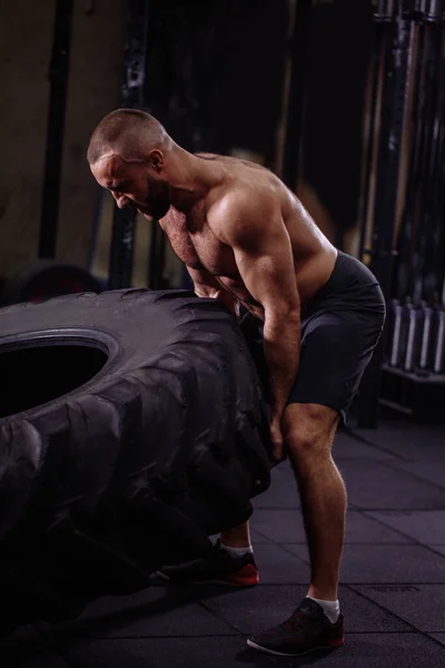 Purposeful athlete with heavy tire. sportsman showing the workshop for friends — Stock Photo, Image