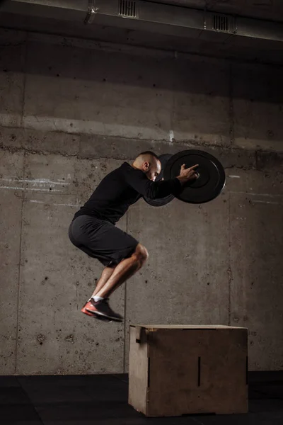 Kraftfull wel-build bodybuilder utför box hopp på gym — Stockfoto