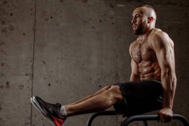 Güçlü kaslı sporcu L 'yi yapıyor. Paralel çubuklarda otur.