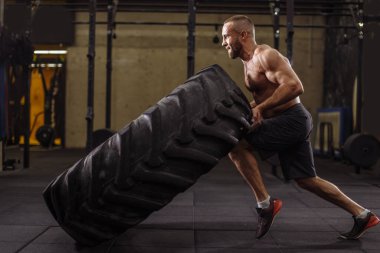 Genç hırslı sporcu ağır lastiklerle eğitimine konsantre oluyor.