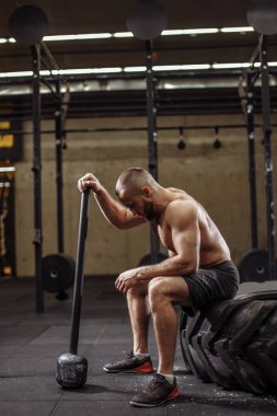 Yorgun adam büyük lastiğin üzerinde oturuyor.