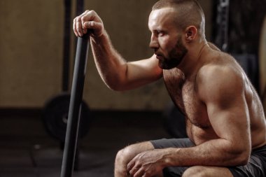 Sside view fotoğrafını kapat. Sakallı, formda adam çekice yaslanıyor.