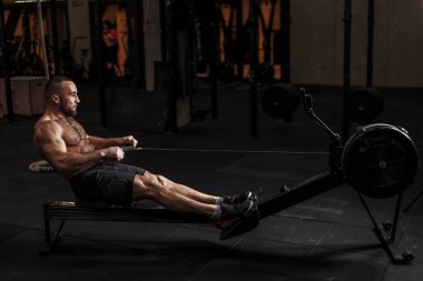 Genç, formda bir adam kürekçiyle egzersize konsantre olur.