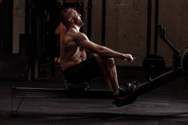 Gülen adam içeride kürekçiyle kaslarını geliştiriyor..