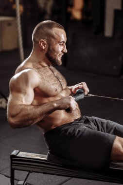 Spor salonunda dişlerini sıkan terli bir adam çalışıyor.