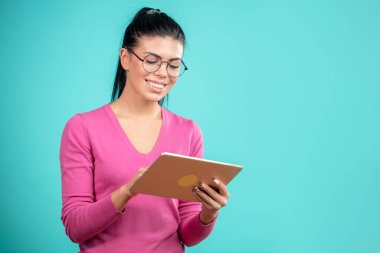 İnternette tabletle sörf yapan hoş bir kız öğrencinin yan görüntüsü.