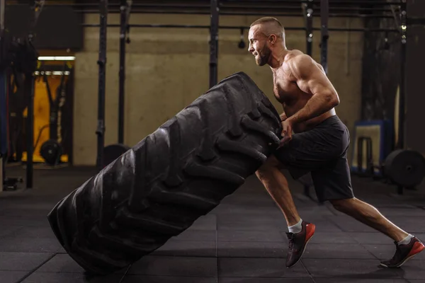 Junger ambitionierter Sportler konzentriert sich auf sein Training mit schweren Reifen — Stockfoto
