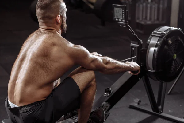 Närbild tillbaka visa foto av en idrottsman utbildning på rad maskin på gym — Stockfoto