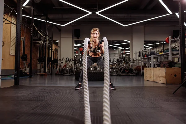 Chica musculosa fuerte usando cuerdas de batalla para el ejercicio — Foto de Stock