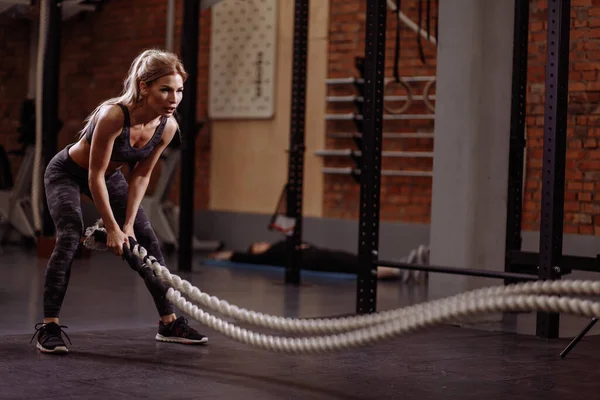 Healthy muscular woman is waving the battle ropes — Stock Photo, Image