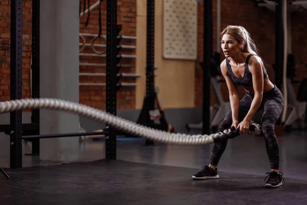 Young pleasant girl training power by slamming the ropes — Stock Photo, Image