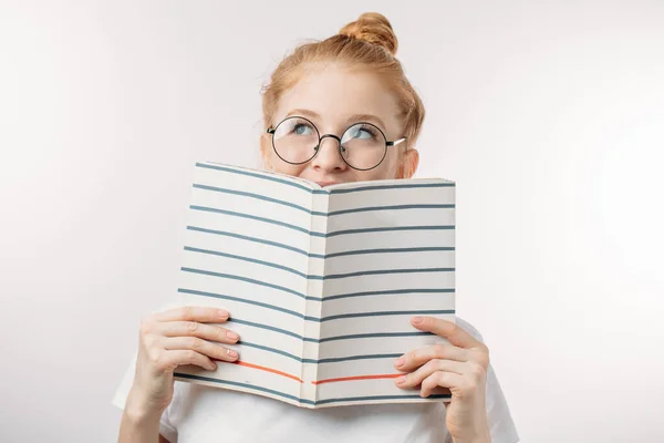 Dromend meisje met een boek voor haar gezicht — Stockfoto