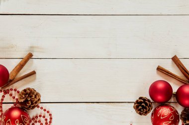 Kırmızı toplarla Noel süslemesi, tarçın, zincir, beyaz ahşap arka planda koniler