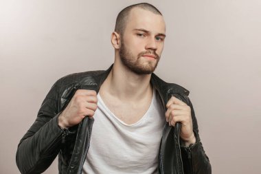 Kameraya poz veren siyah ceketli, modaya uygun genç bir adam.