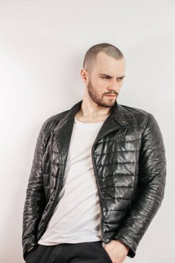 Düşünceli yakışıklı genç erkek beyaz duvara yaslanıyor ve yan bakıyor.