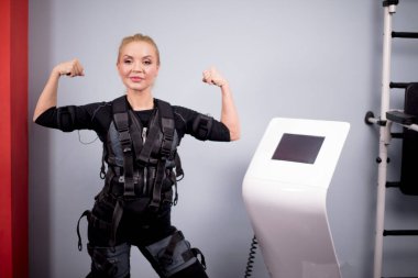 Neşeli sarışın kız güçlü kollarını gösteriyor.