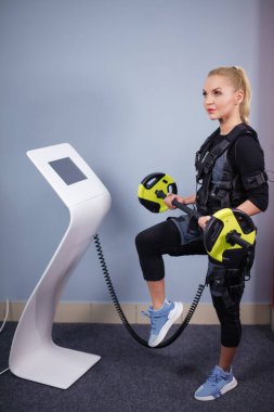 Sarışın sporcu kız ağırlık ve beden eğitimi hocasıyla egzersiz yapıyor.