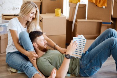 Kitaplı çift yeni eve taşınırken yatakta oturuyor.