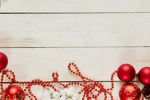 Décoration de Noël avec boules rouges, cannelle, chaîne, cônes sur fond de bois blanc — Photo