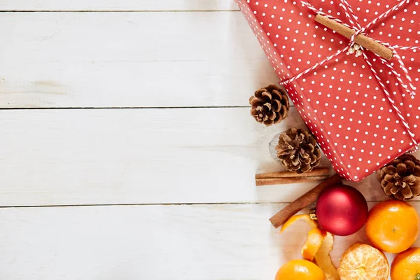 Couché à plat, vue de dessus. Composition de Noël. cadeau, tricot, cônes, branches sur fond blanc en bois. — Photo