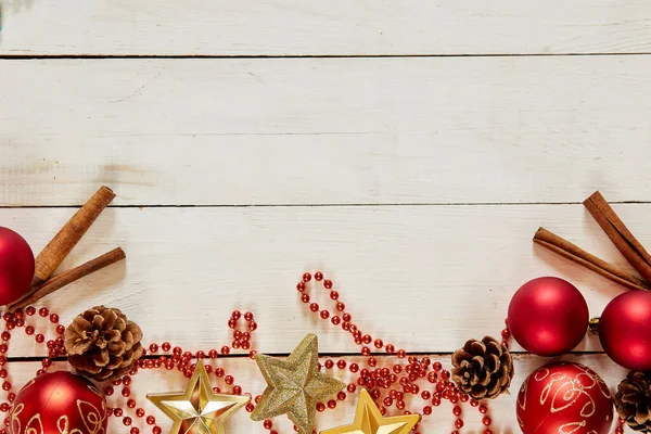 Décoration de Noël avec boules rouges, cannelle, chaîne, cônes sur fond de bois blanc — Photo