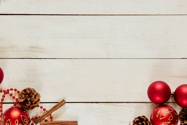 Décoration de Noël avec boules rouges, cannelle, chaîne, cônes sur fond de bois blanc — Photo